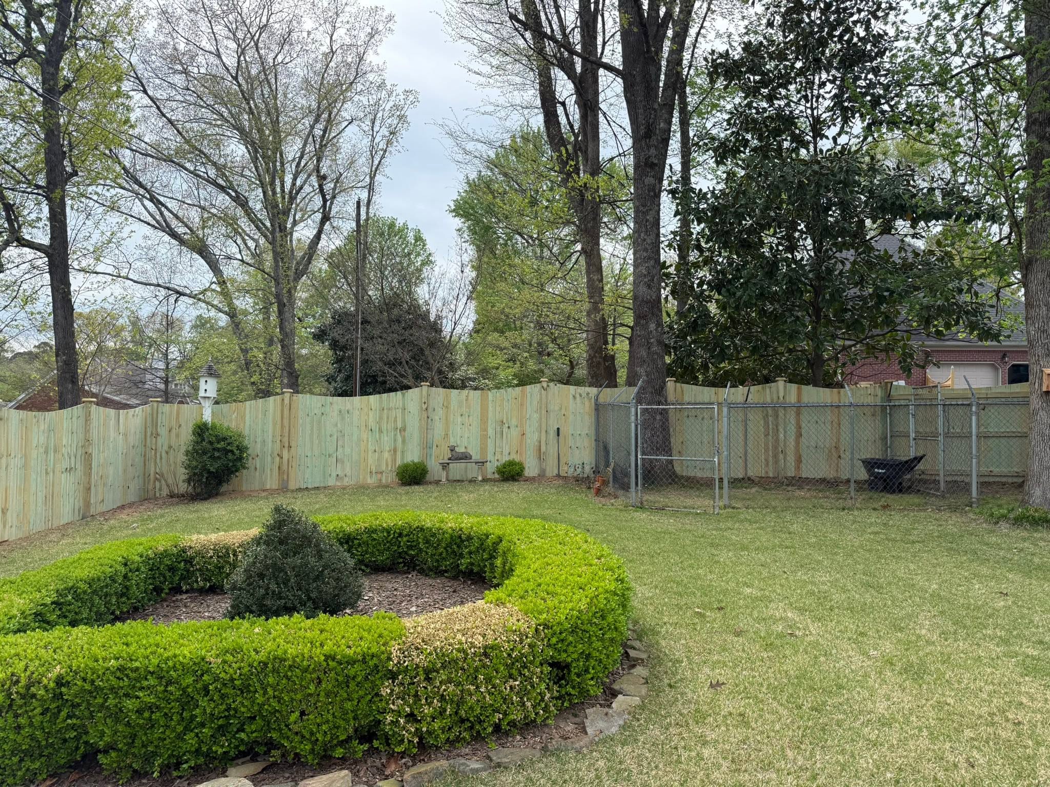 Scalloped-top wood privacy fence and chain-link dog run in Northern Alabama
