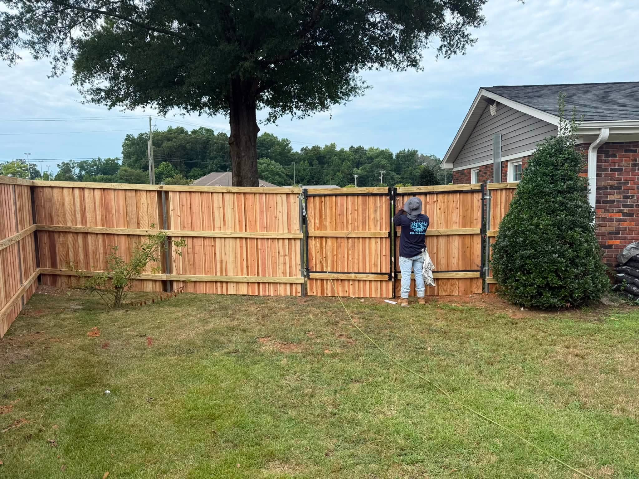 Vaughn Fence crew finishing a wooden privacy fence double gate in Colbert County, AL