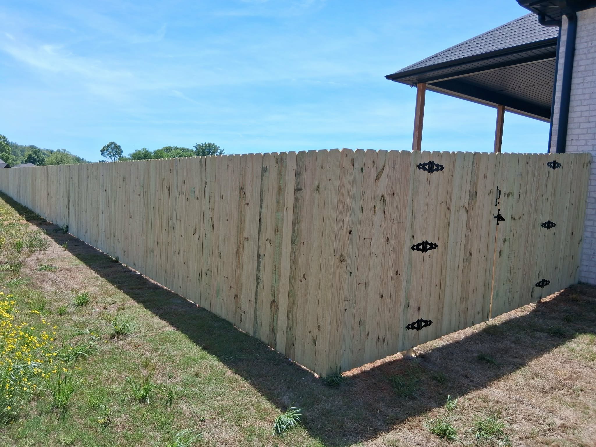 Dog-ear wood privacy fence with black gate hardware in Muscle Shoals, AL