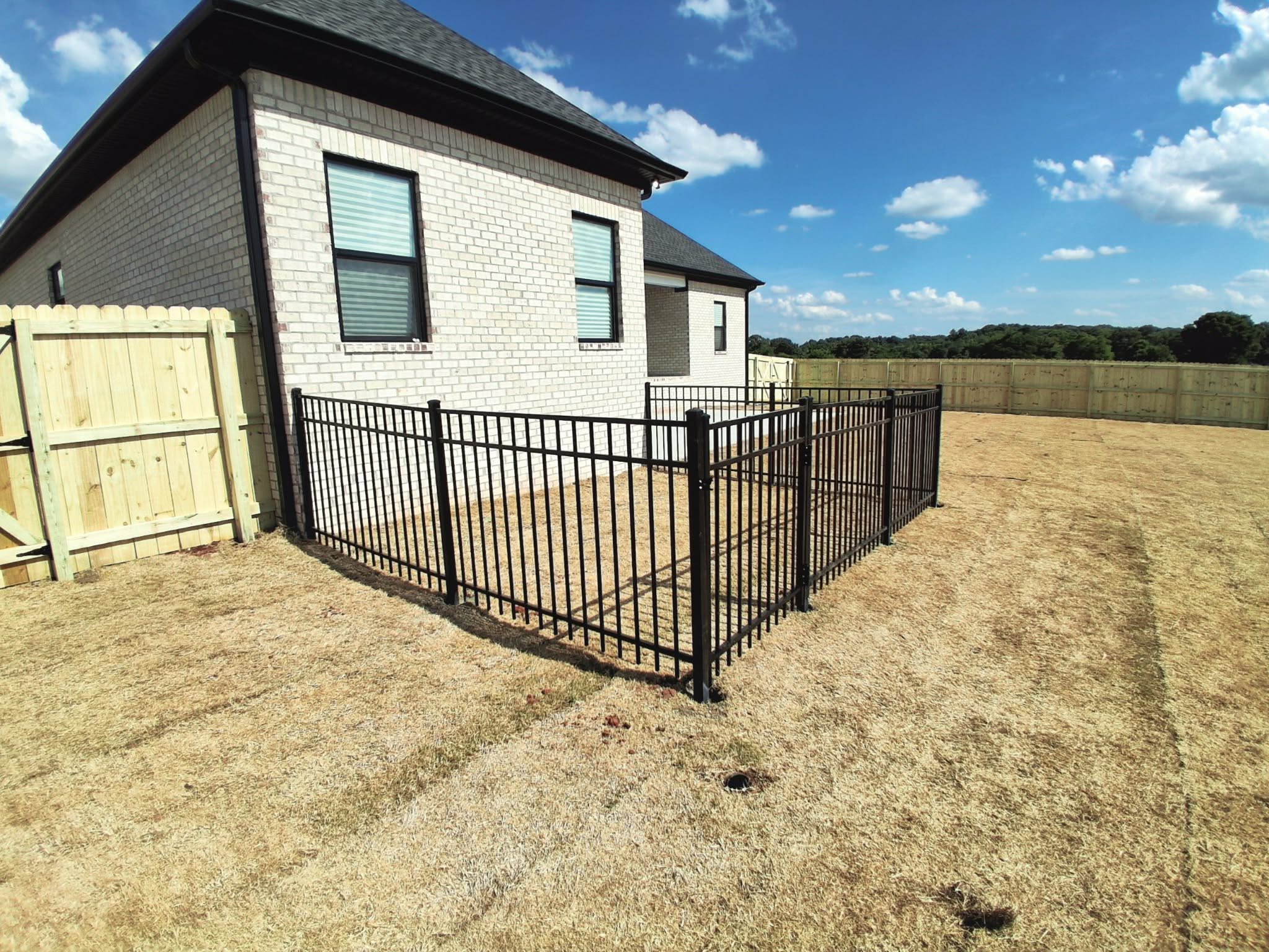 Black ornamental metal patio enclosure beside a brick home in Muscle Shoals, AL