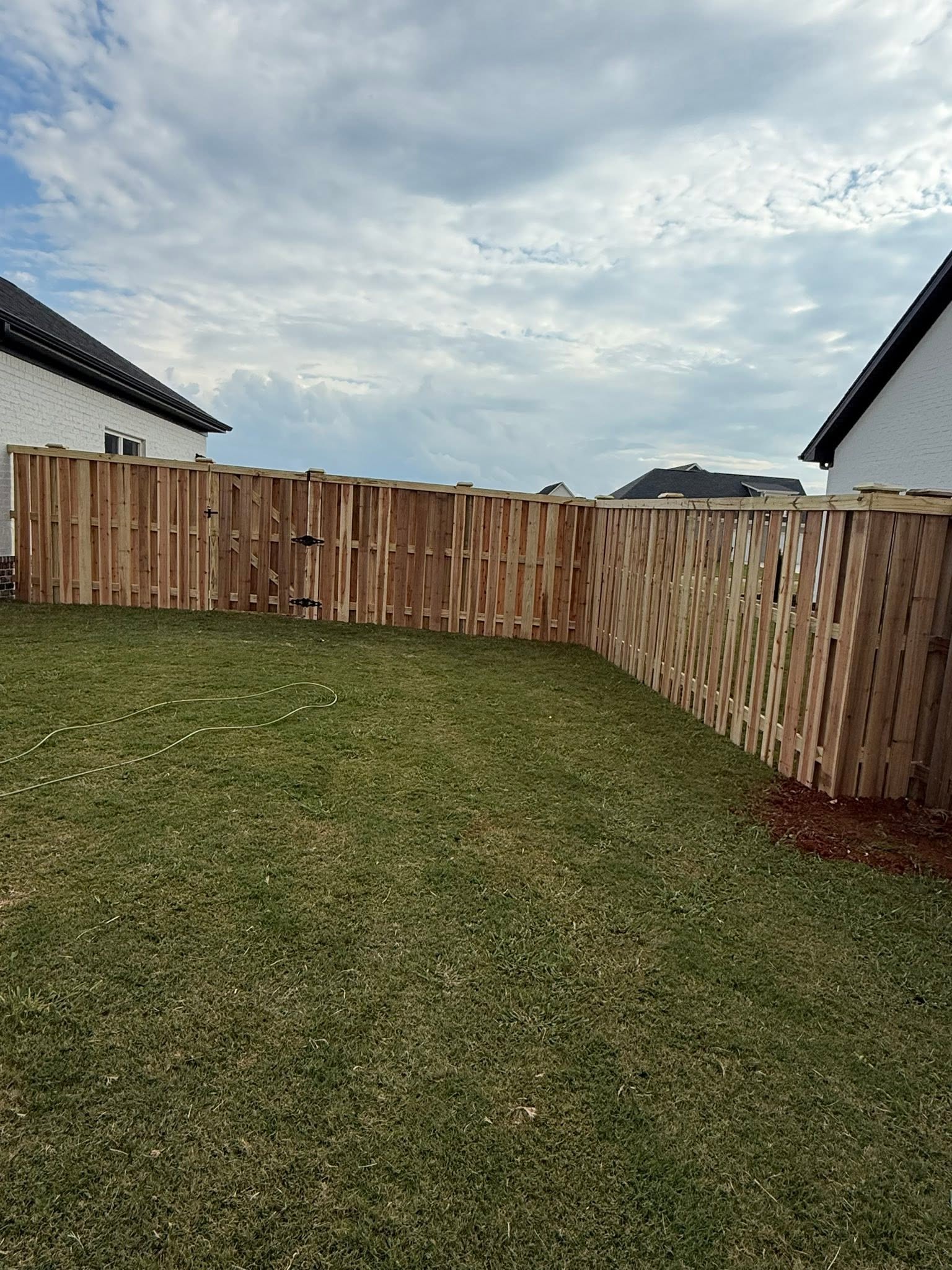 Residential wood privacy fence with double gate corner install in Muscle Shoals, AL