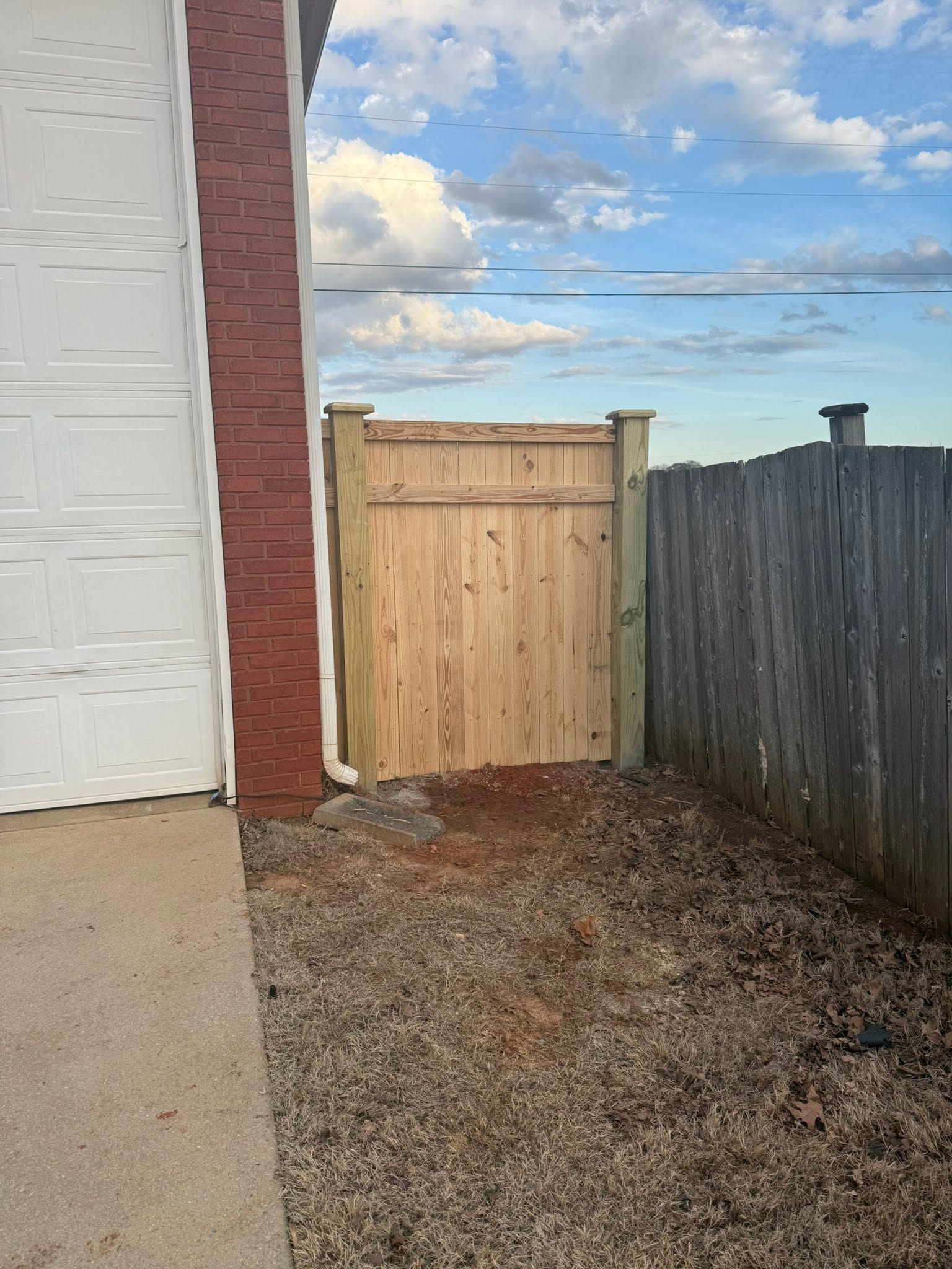 Side-yard wood fence gate connecting brick garage and existing fence in Colbert County, AL