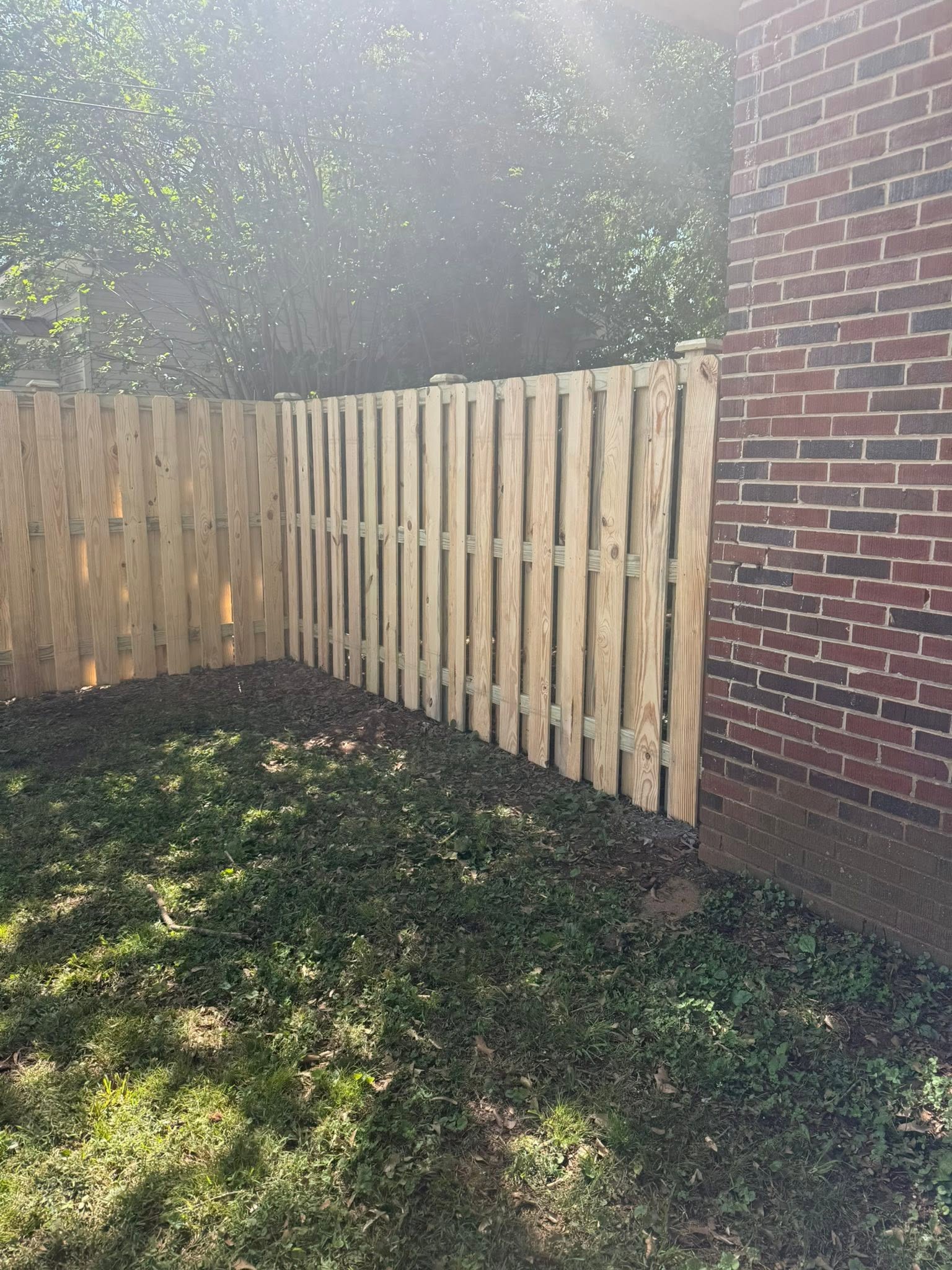 Shadowbox wood privacy fence along a brick home in Muscle Shoals, AL