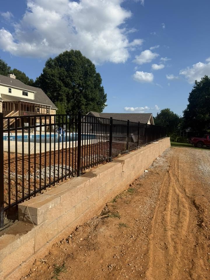 Black metal fence on concrete retaining wall near a pool in Muscle Shoals, AL
